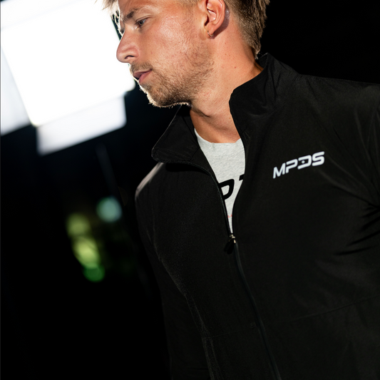 Man wearing a black jacket with 'MPDS' logo against a dark background